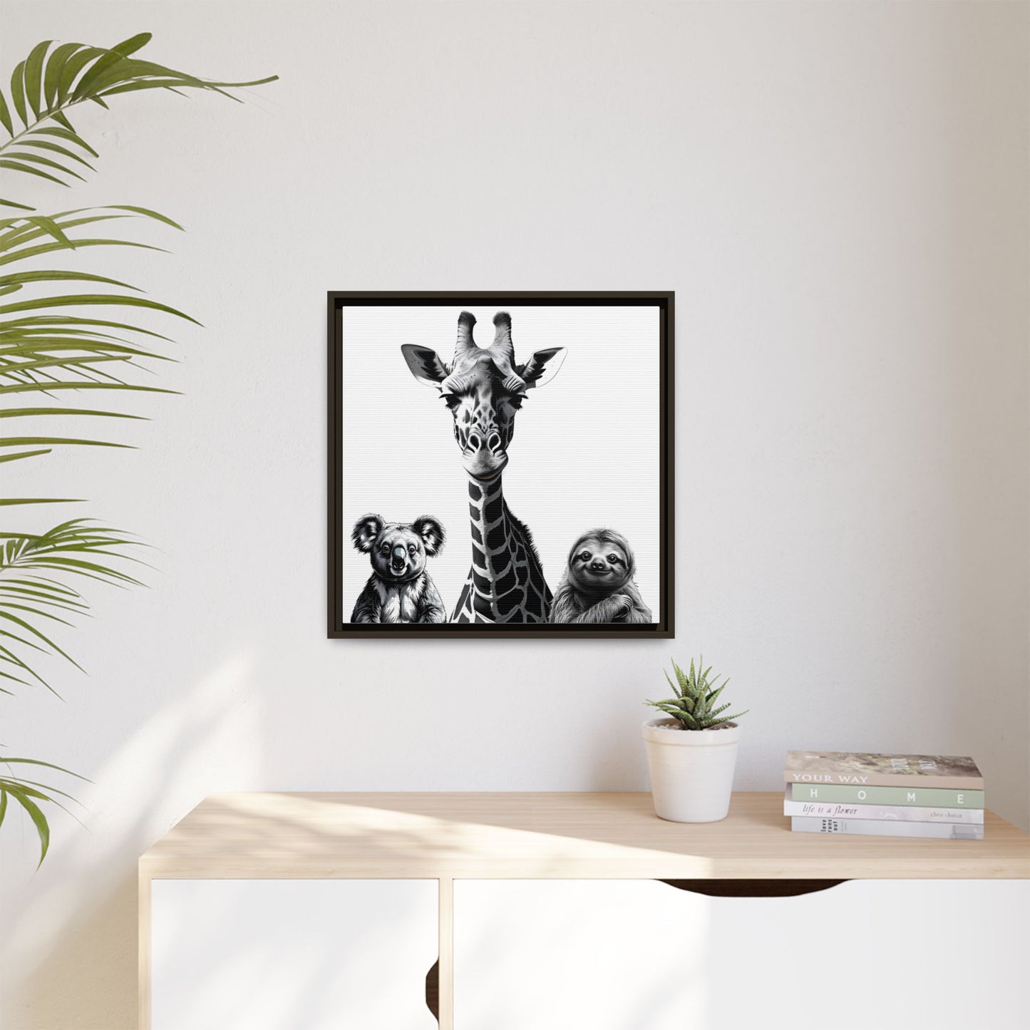 Framed artwork of a giraffe, koala, and sloth on a wall above a desk with plants.
