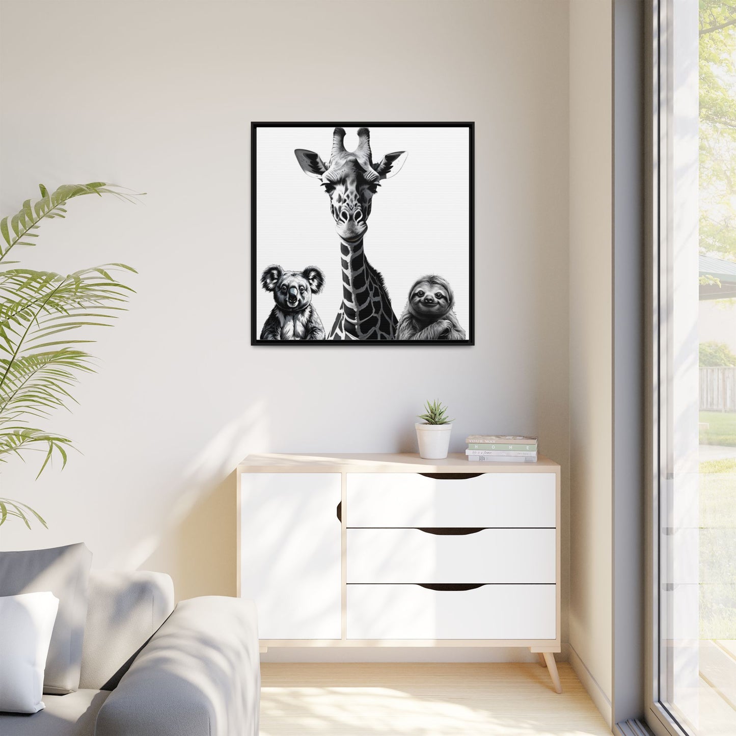 Framed artwork of a giraffe and sloths on a wall above a white cabinet.