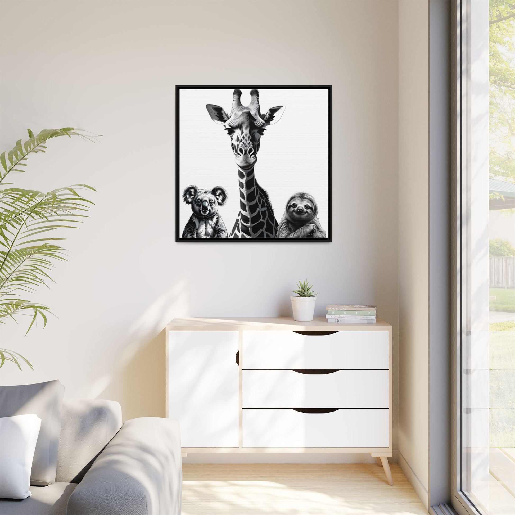 Framed artwork of a giraffe and sloths on a wall above a white cabinet.