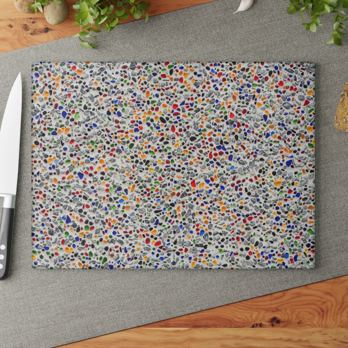 Colorful speckled placemat on a gray surface with a knife and wooden board.