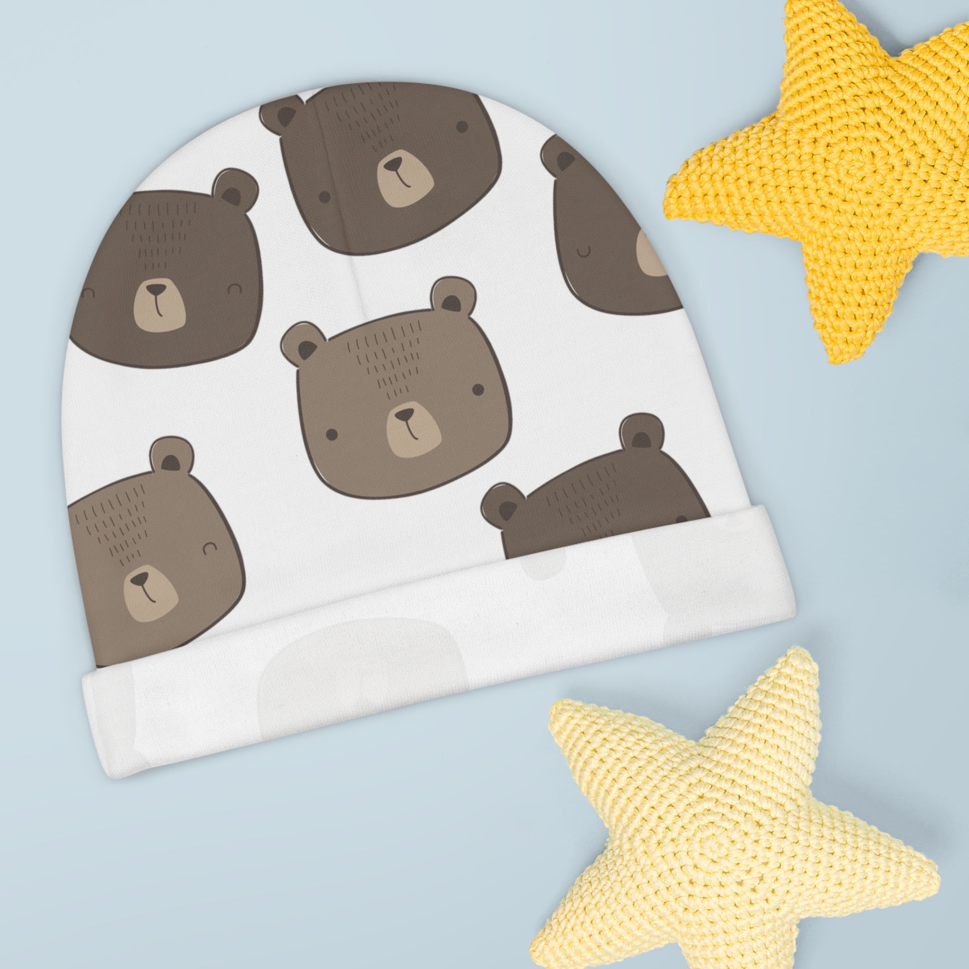 White baby hat with brown bear pattern on a light blue background with yellow stars.