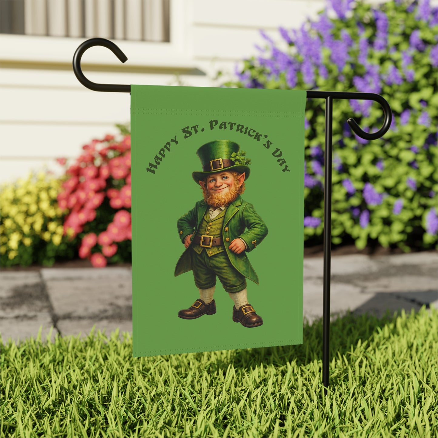 St. Patrick's Day garden flag with a leprechaun design on grass with flowers in the background