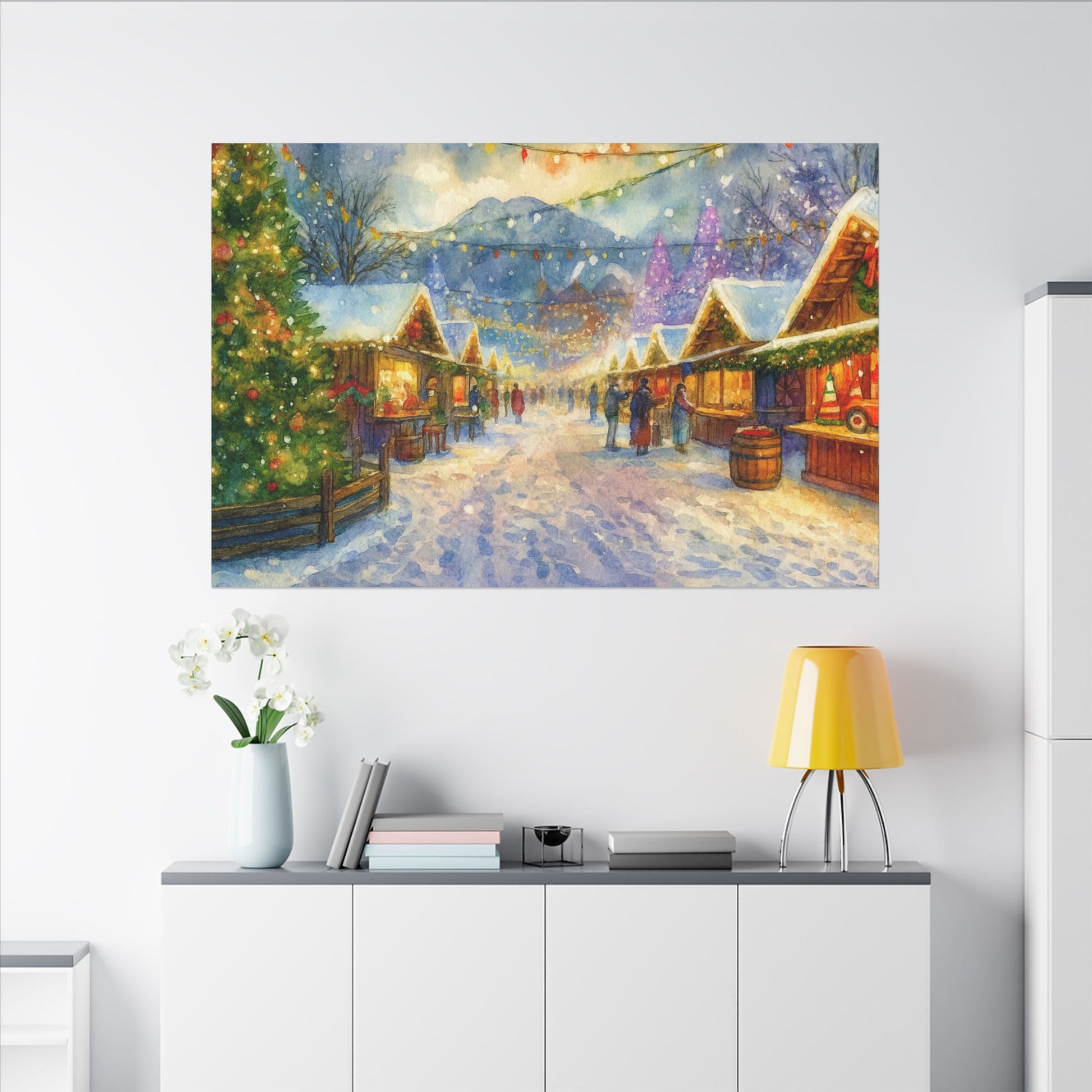 Winter village scene painting on a wall above a white cabinet with a lamp and books.