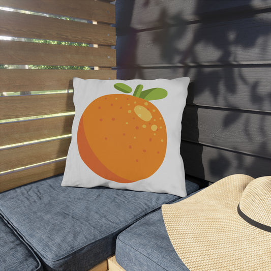 Pillow with an orange design on a outdoor bench with a hat nearby