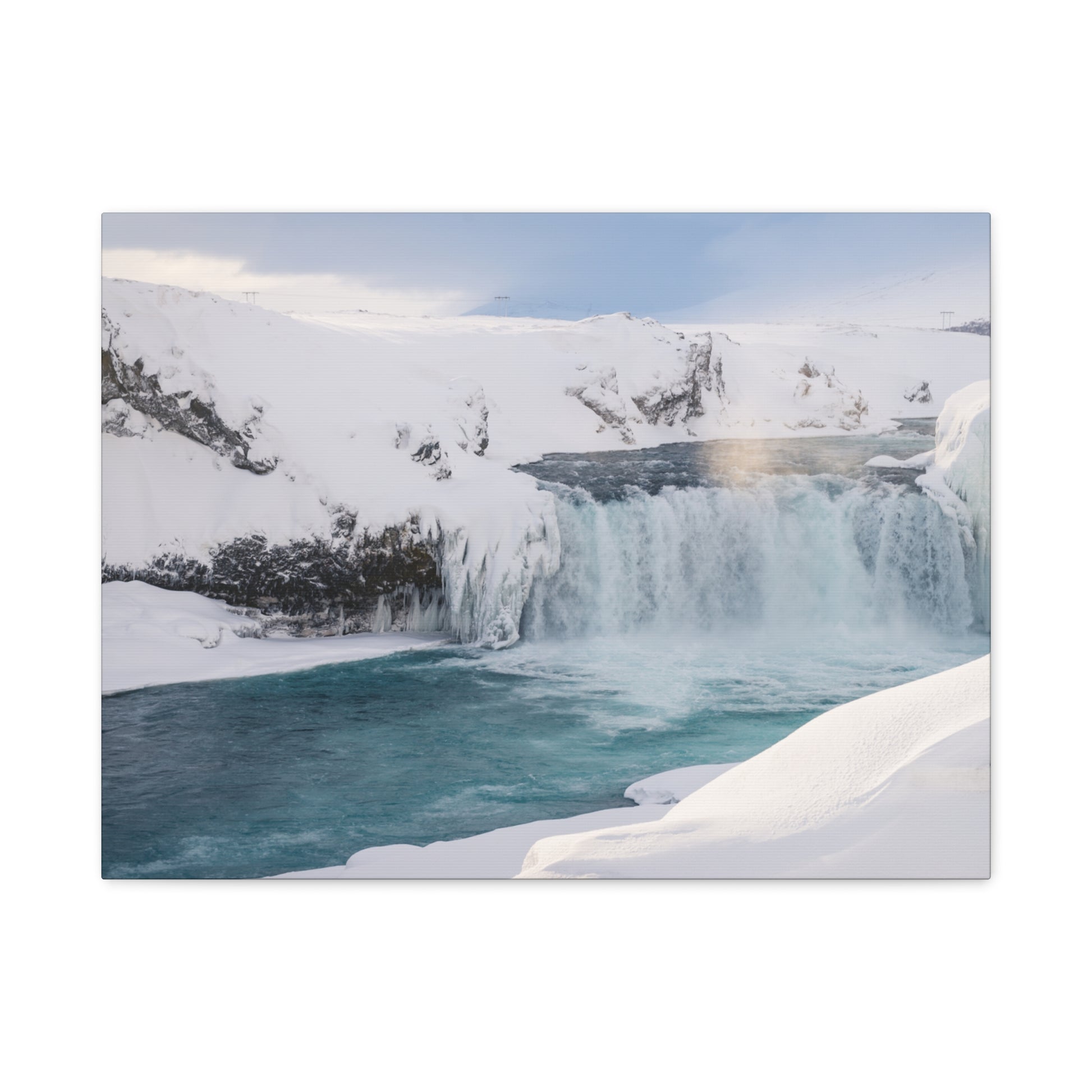 Frozen waterfall in a snowy landscape with a rainbow in the mist.
