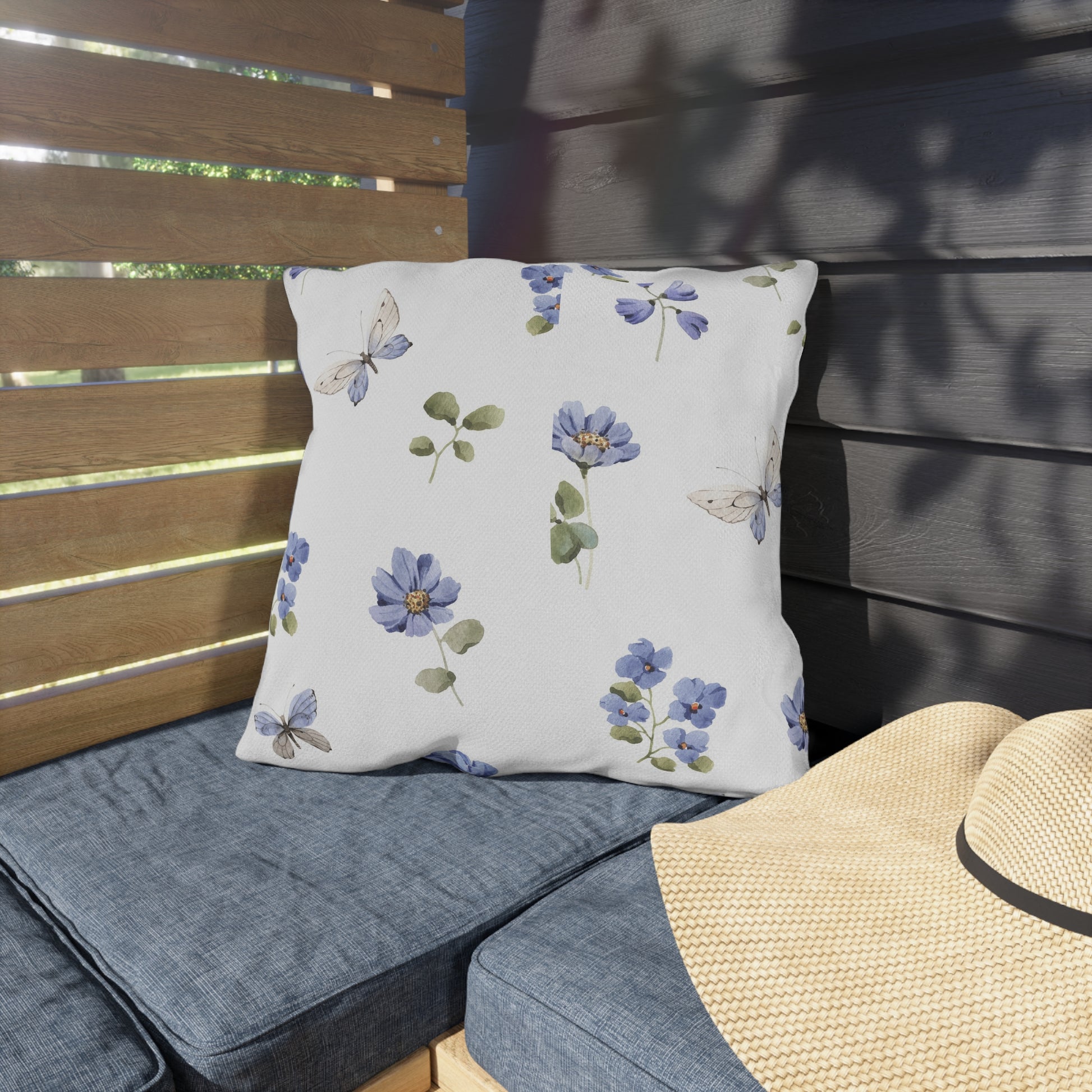 Floral-patterned cushion on a wooden bench with a straw hat nearby.