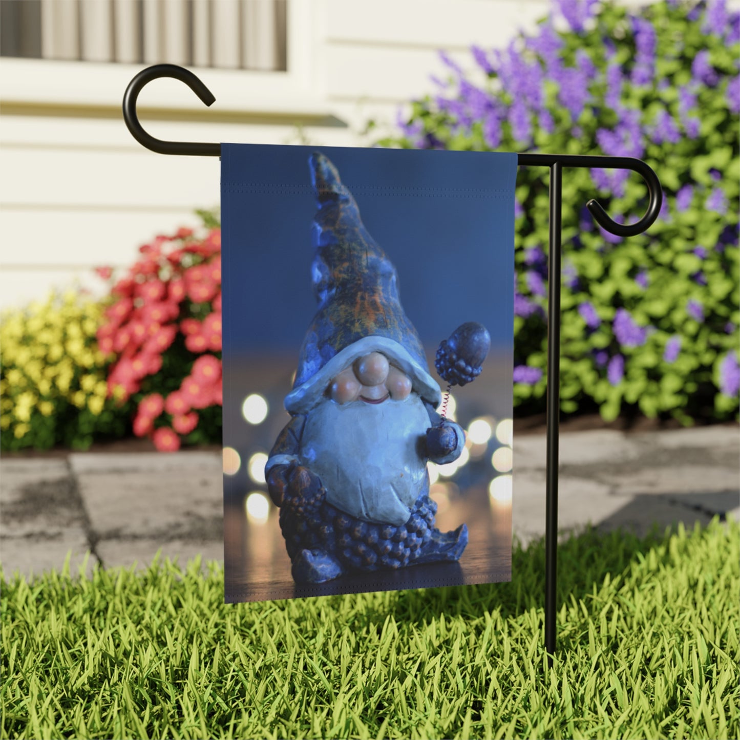 Gnome-themed garden flag on a stand with flowers in the background