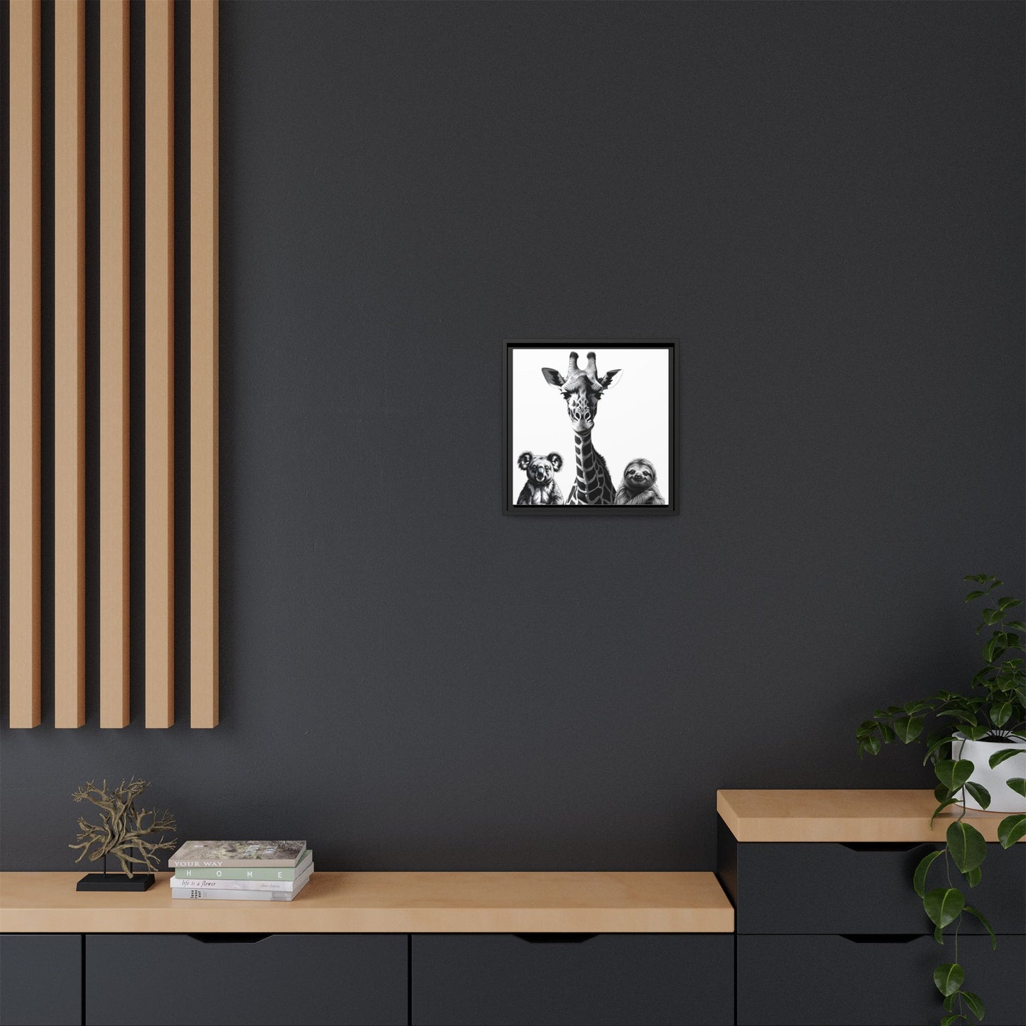Framed black and white artwork of a giraffe and two cubs on a dark wall above a wooden shelf.