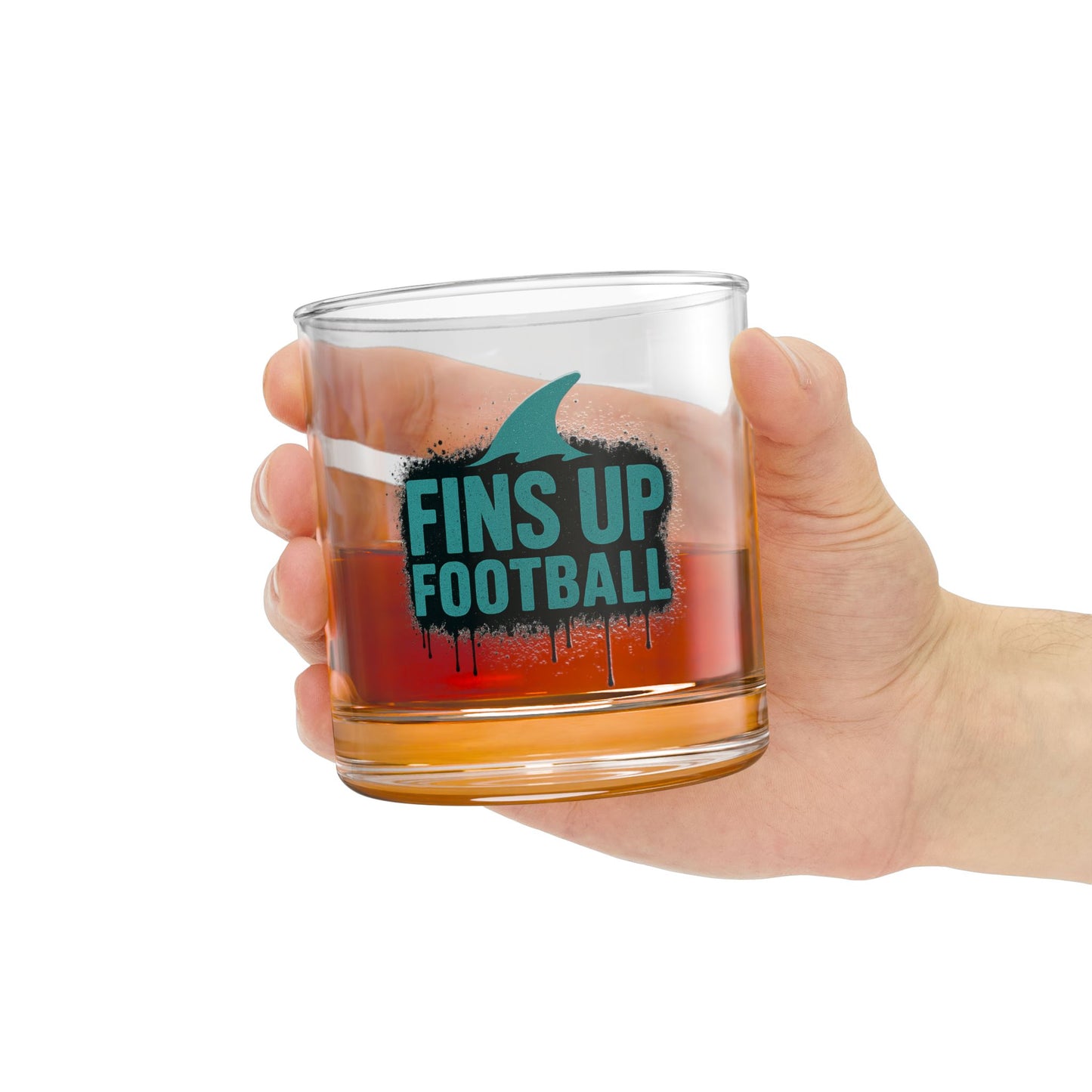 Hand holding a clear glass mug with 'FINS UP FOOTBALL' text, filled with a dark liquid on a white background.