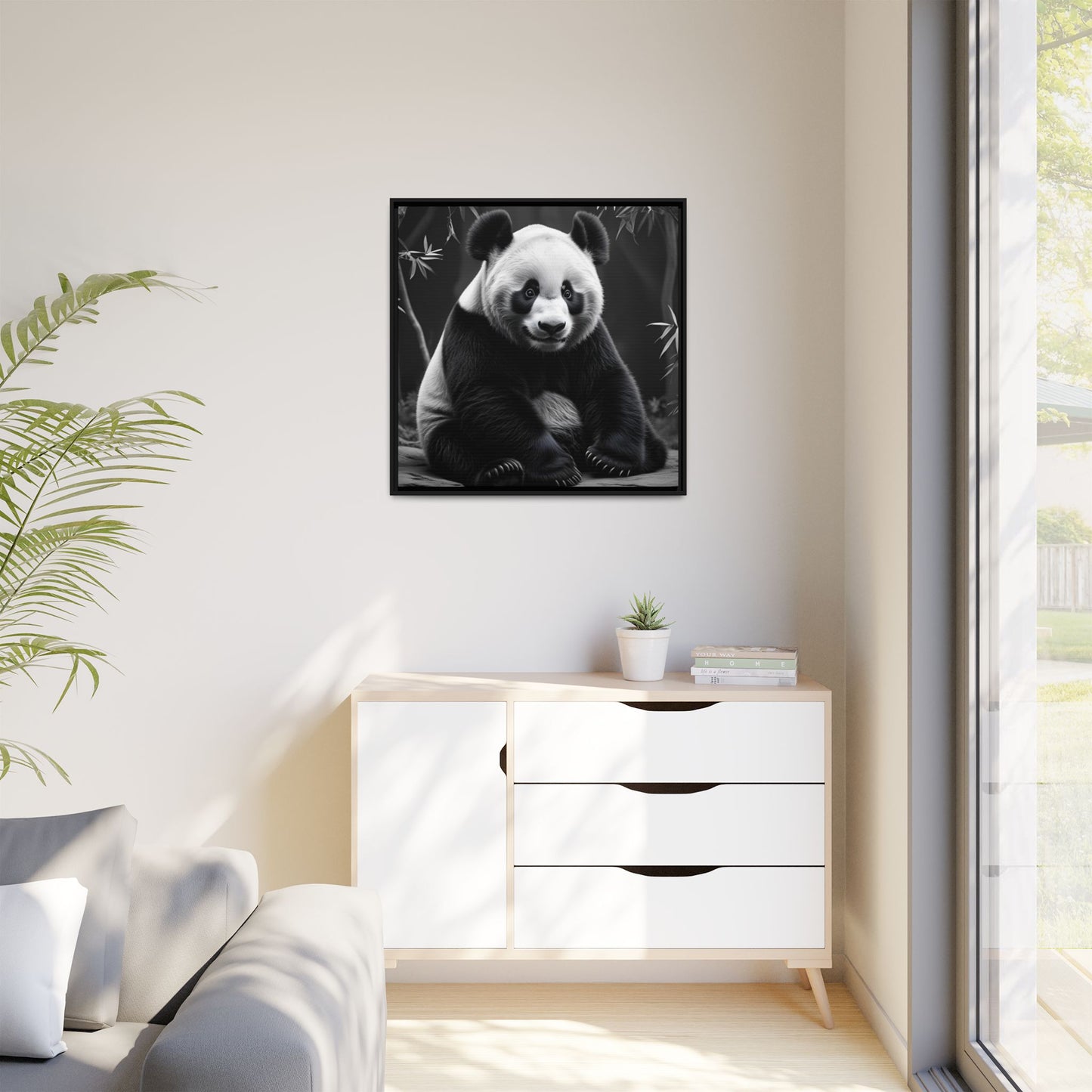 Framed black and white photo of a panda on a wall above a white cabinet.
