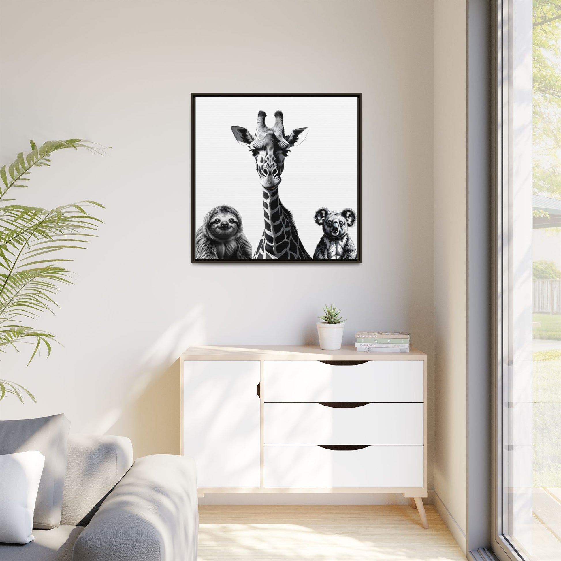 Framed artwork of a giraffe, sloth, and koala on a wall above a white cabinet.