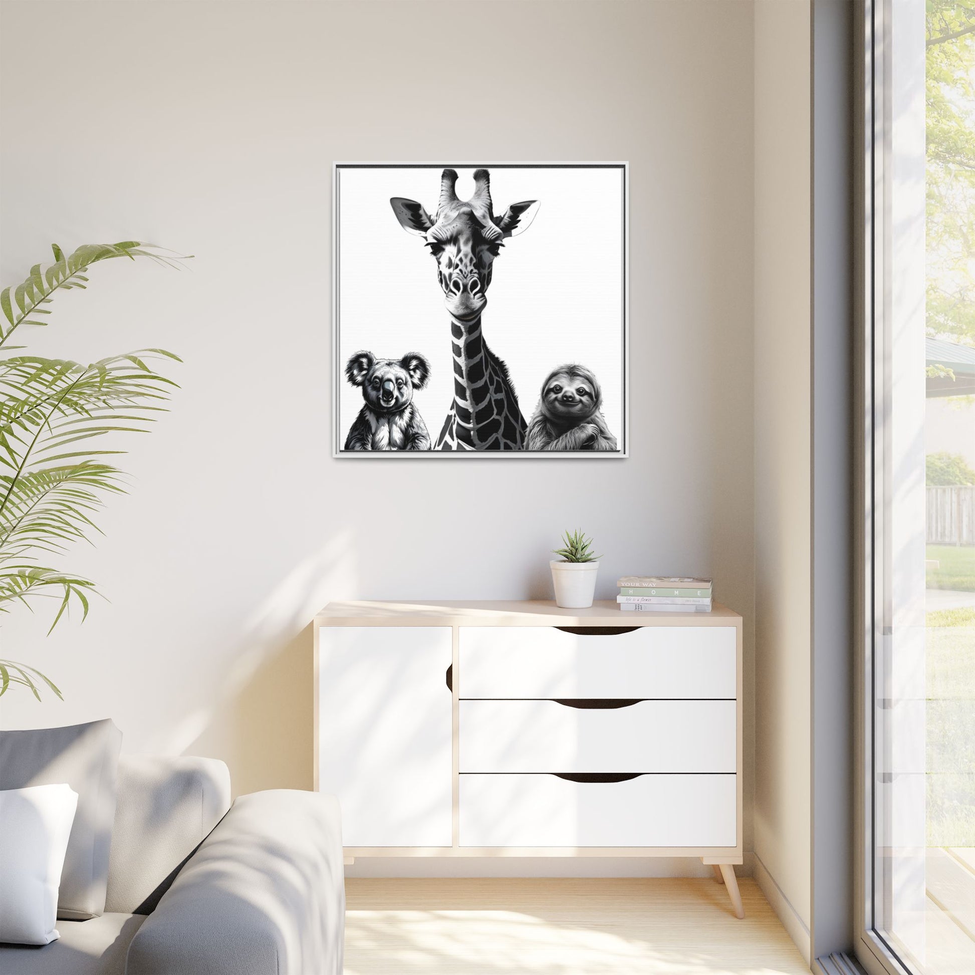 Framed artwork of a giraffe and sloths on a wall above a white cabinet.
