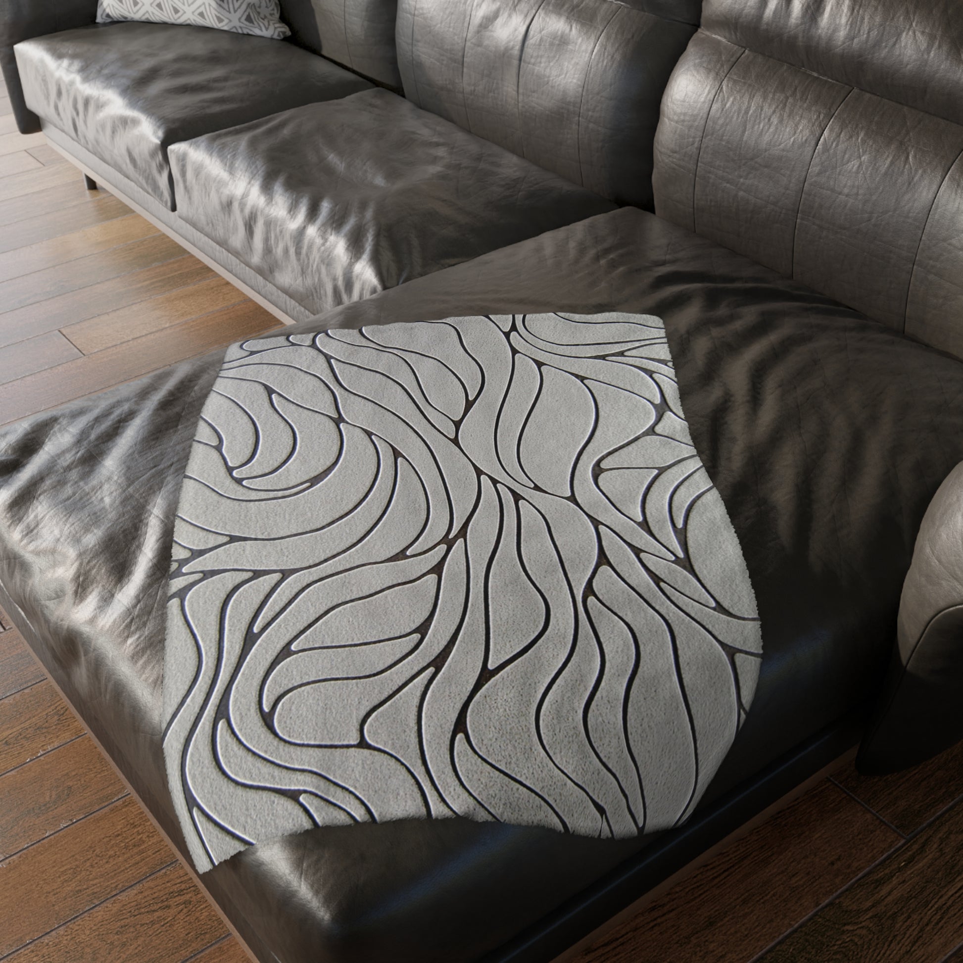 Gray textured ottoman with wavy pattern on a dark brown leather sofa.