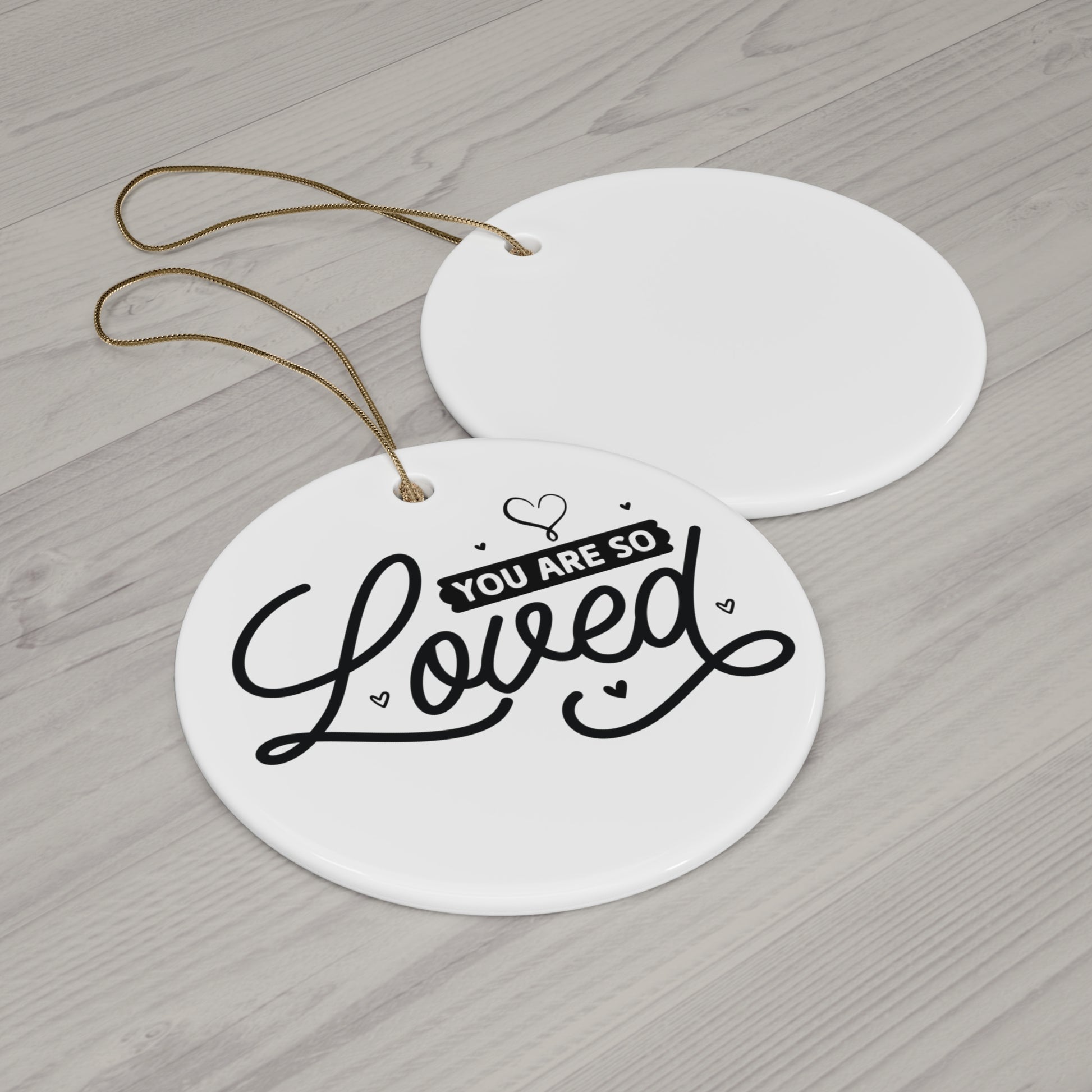 Round white tag with 'You are so loved' text on a wooden surface