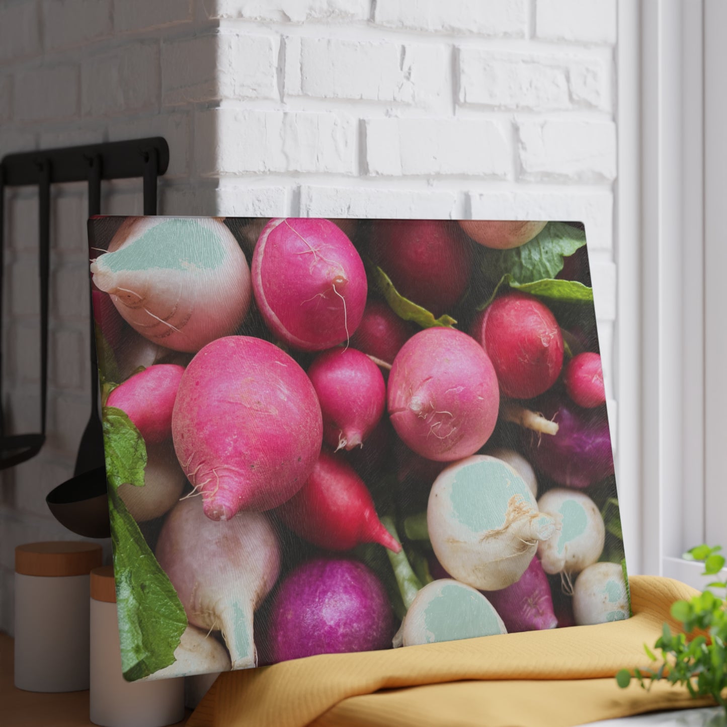 Framed picture of radishes on a kitchen counter with a white brick wall background