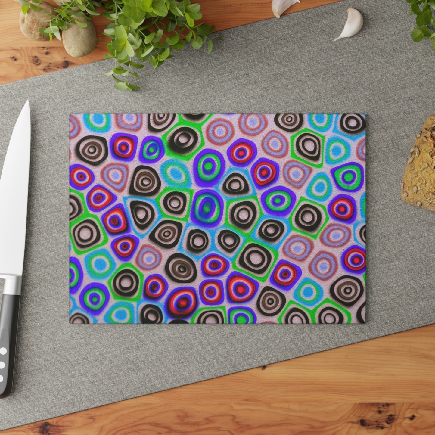 Colorful circular patterned cutting board on a wooden surface with a knife and plant.