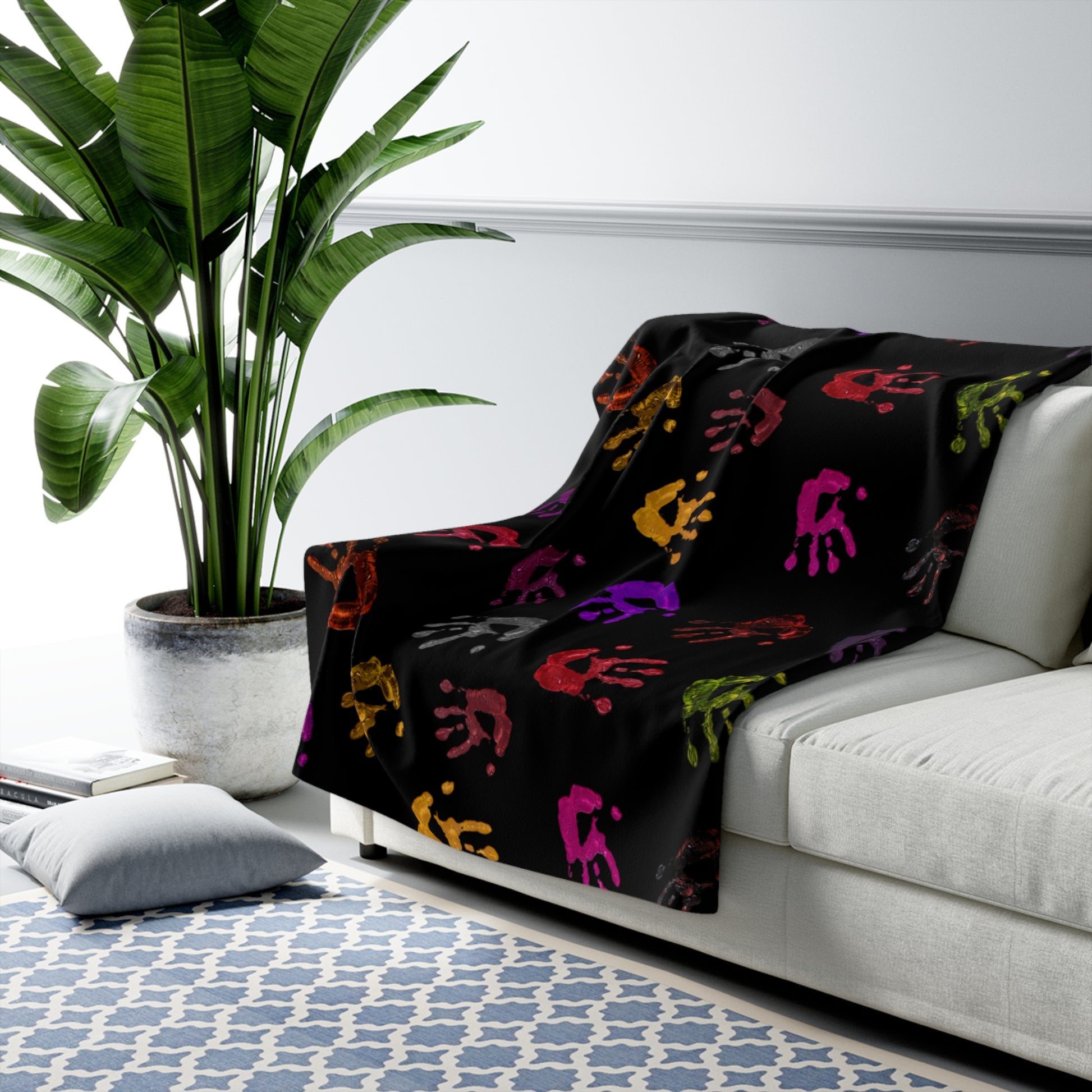 Black blanket with colorful patterns draped over a white sofa in a living room setting.