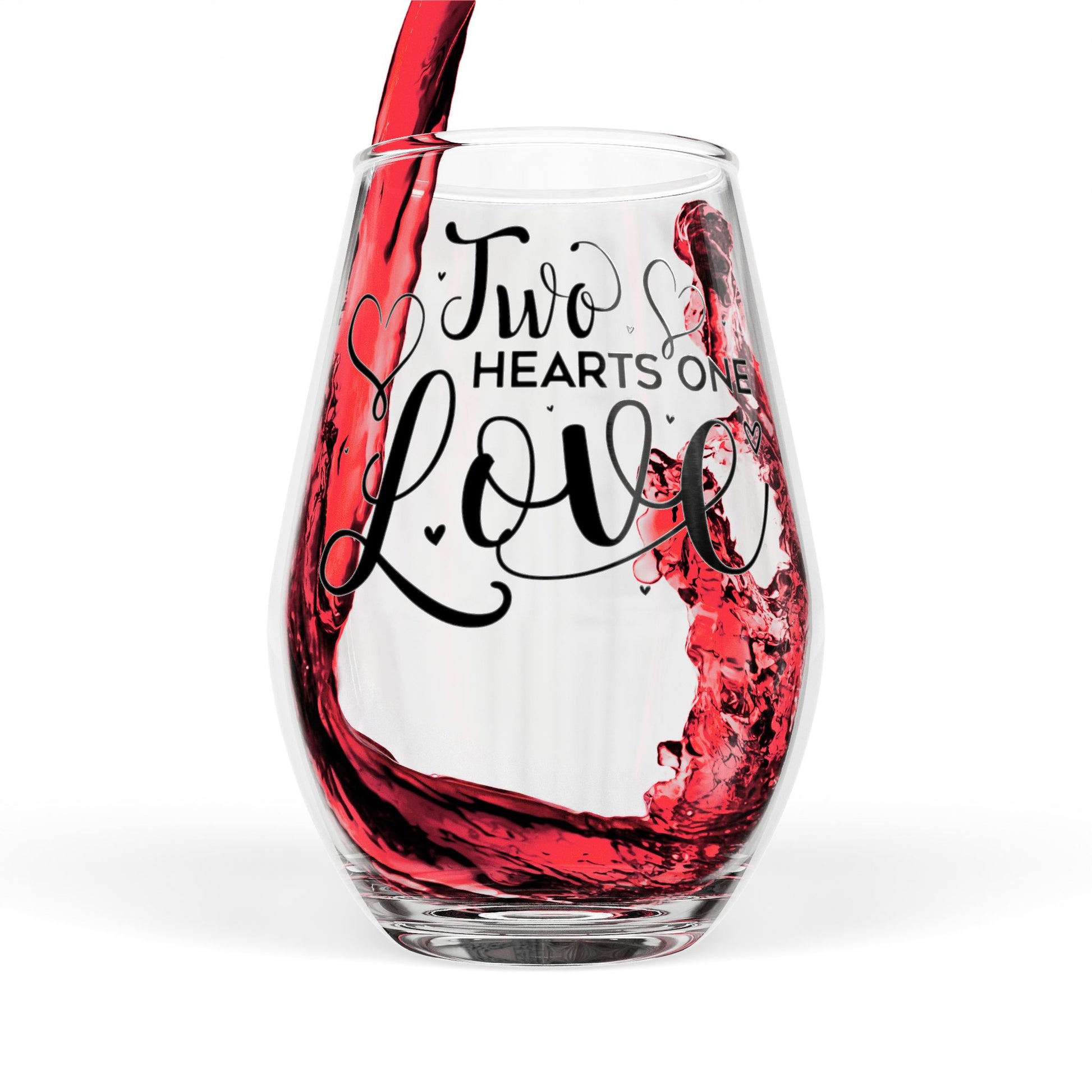 Clear wine glass with 'Two Hearts One Love' text being filled with red wine.