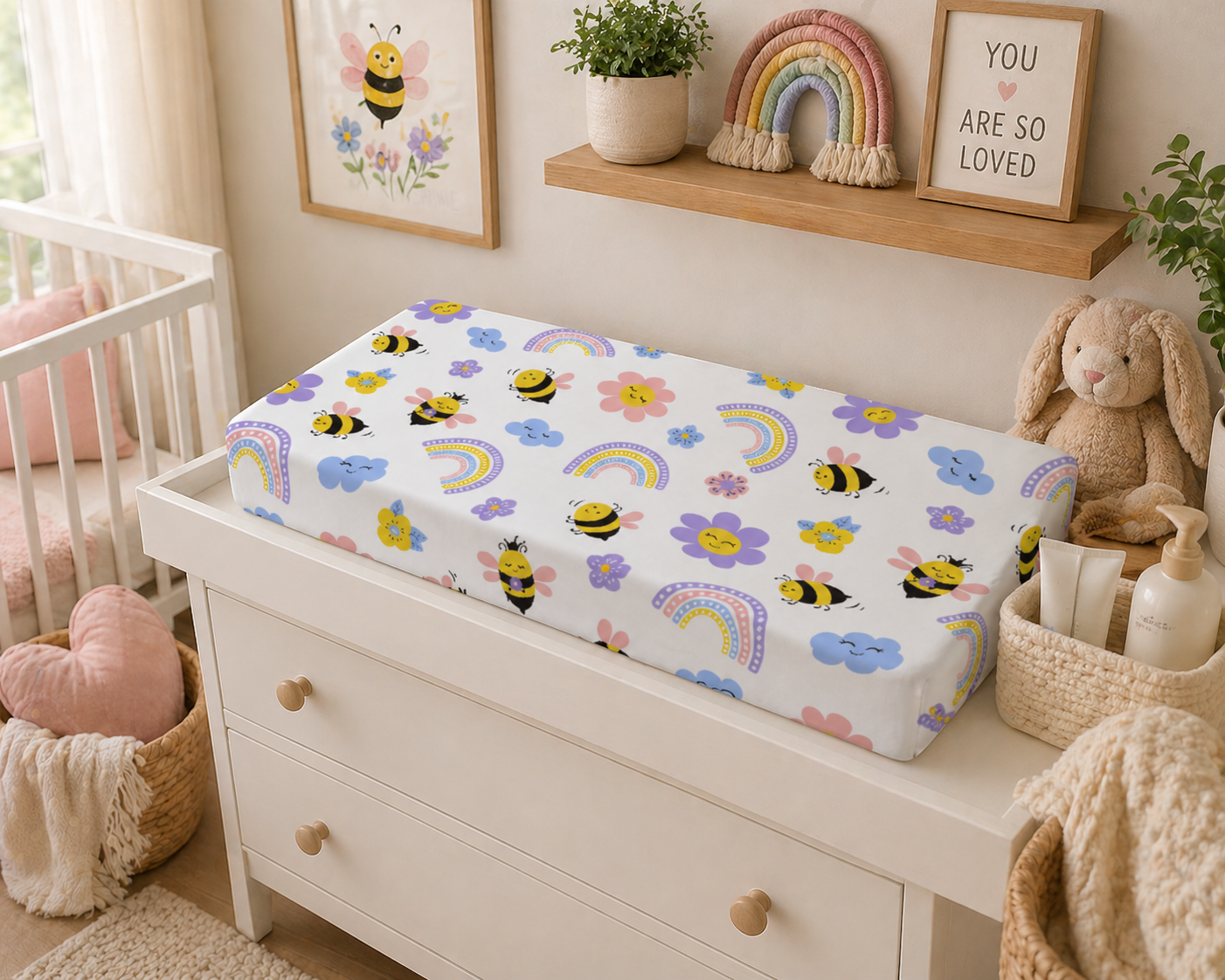 Nursery with a changing table covered by a colorful baby blanket featuring bees, flowers, and rainbows.