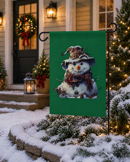 Decorative garden flag with a snowman design on a green background, displayed outdoors in front of a house with Christmas decorations.