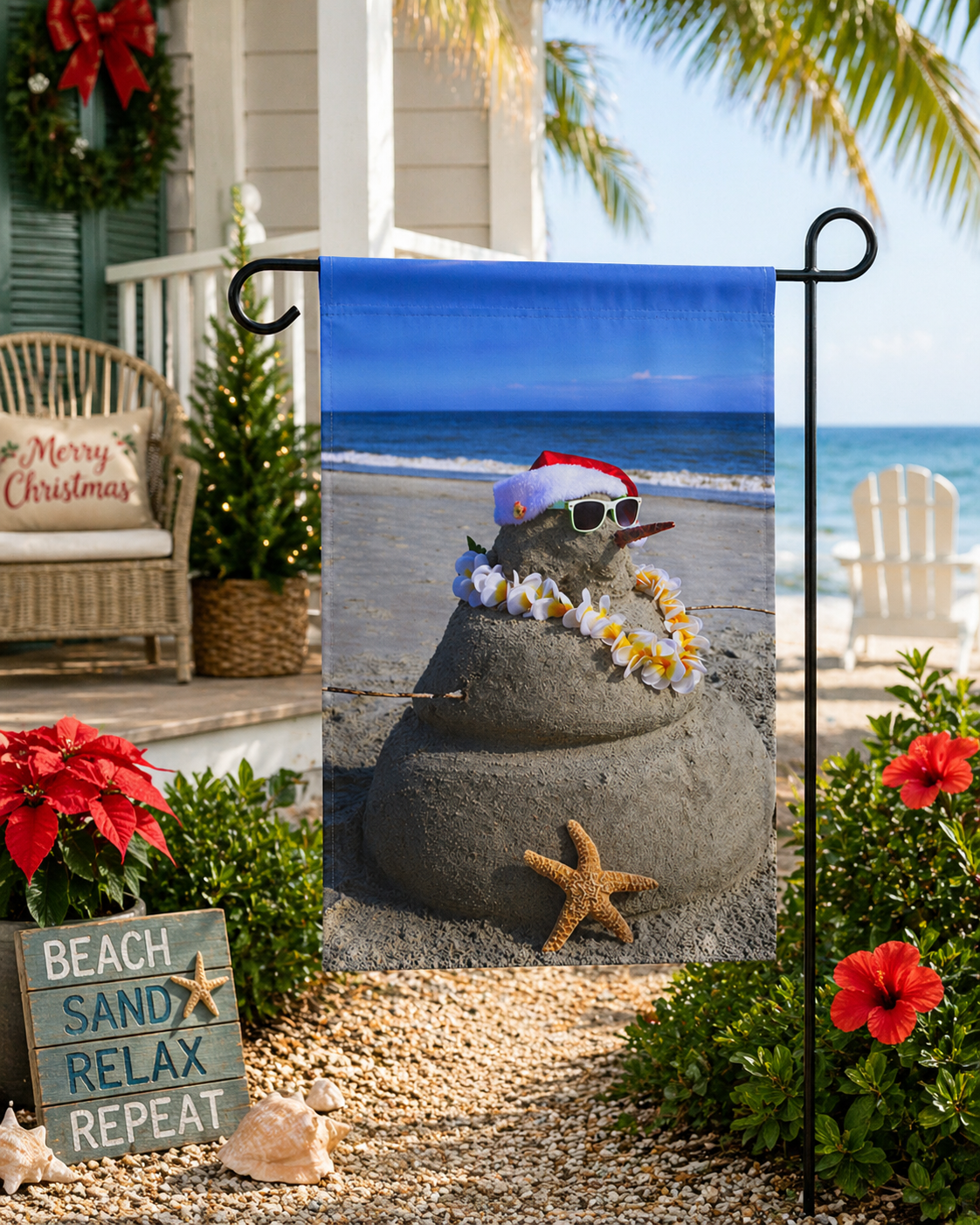 Decorative garden flag with sandcastle design on a beach, surrounded by Christmas decorations.