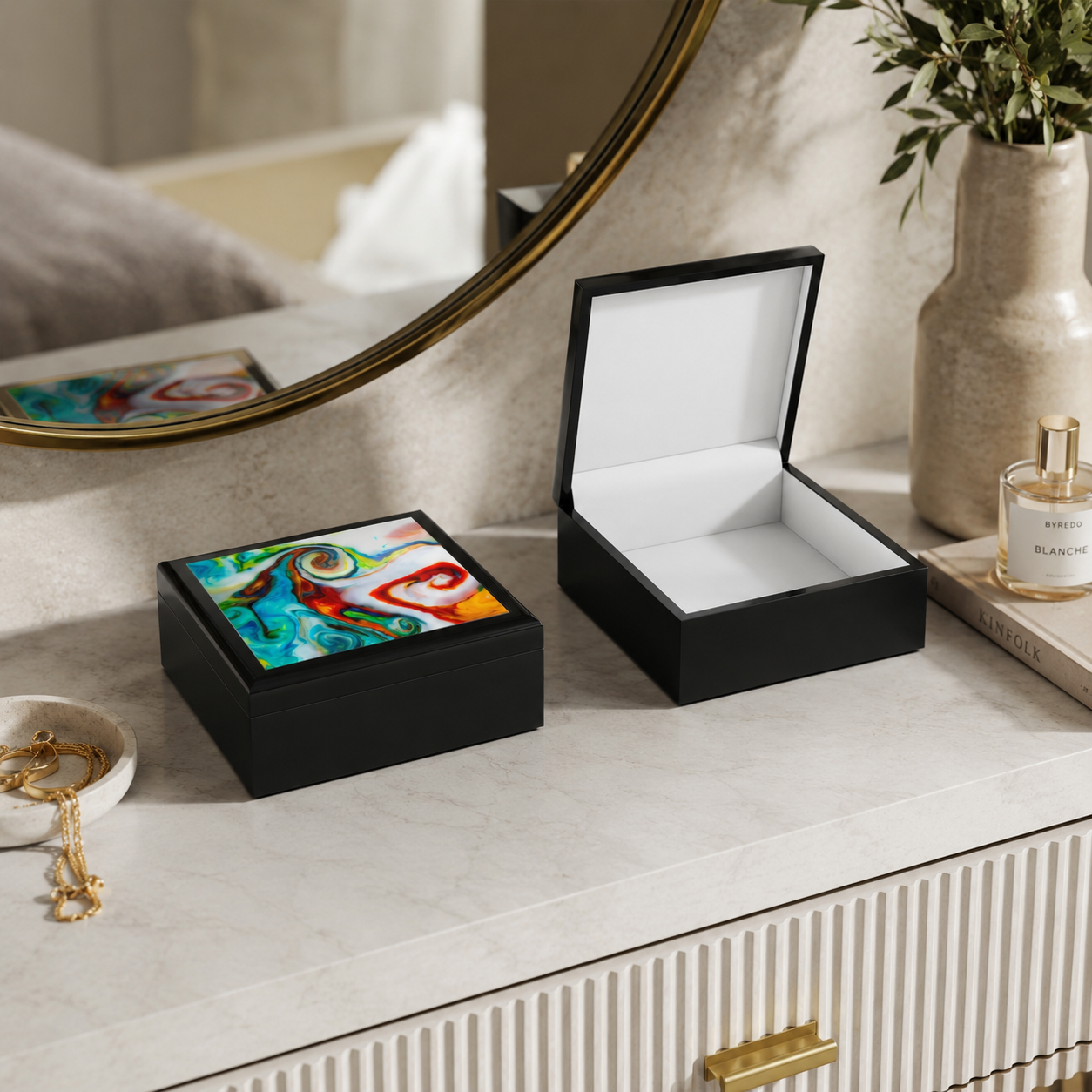 Two black jewelry boxes on a dresser with a mirror and decorative items in the background.