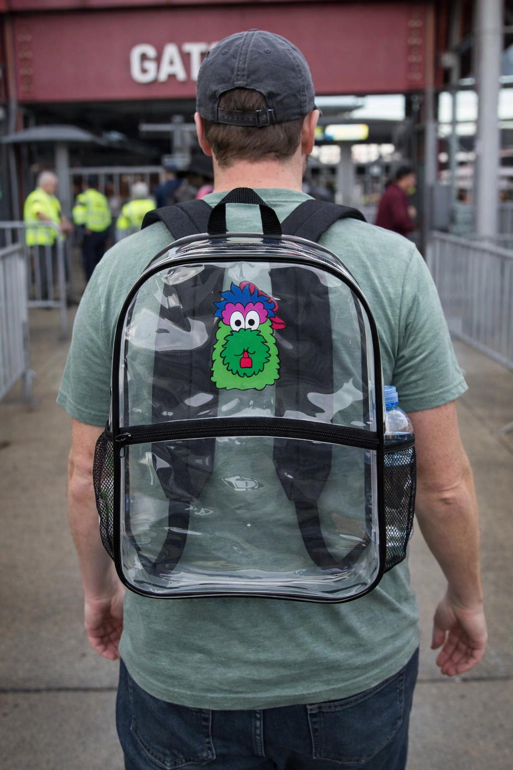 Person wearing a transparent backpack with a colorful monster design at an outdoor location.